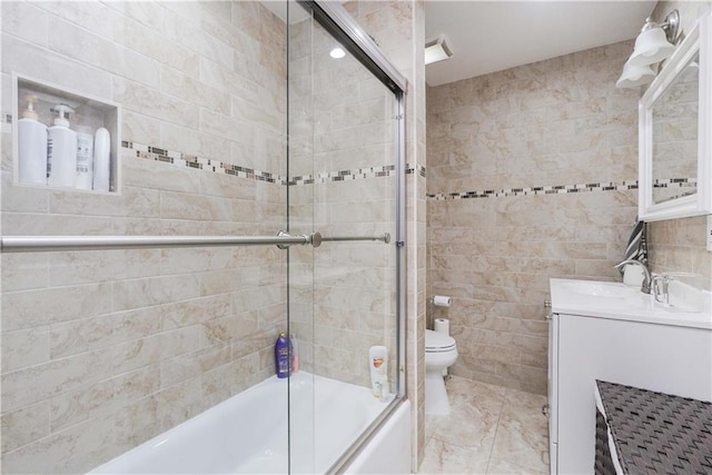 full bathroom with shower / bath combination with glass door, vanity, tile walls, and toilet