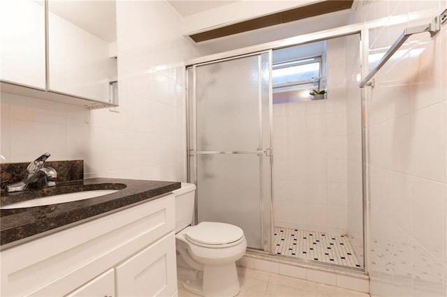 bathroom with vanity, tile patterned flooring, toilet, walk in shower, and tile walls