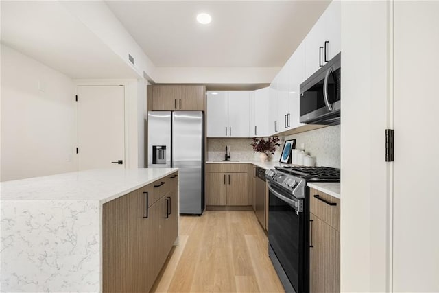 kitchen featuring decorative backsplash, stainless steel appliances, a kitchen island, and light wood-type flooring