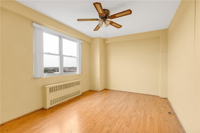 unfurnished room featuring ceiling fan, radiator heating unit, and light hardwood / wood-style floors