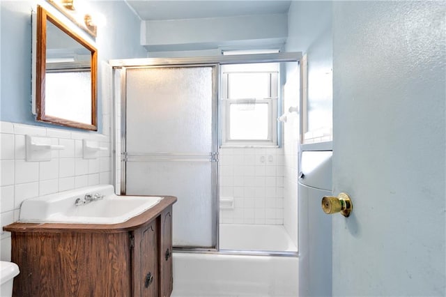 full bathroom with vanity, toilet, combined bath / shower with glass door, and tile walls