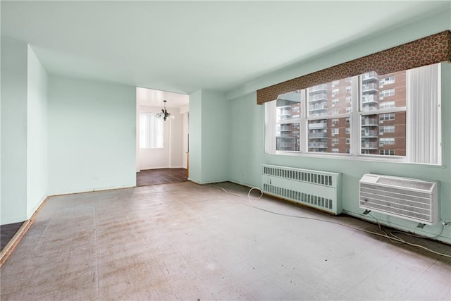 empty room with radiator, a wall mounted AC, and an inviting chandelier