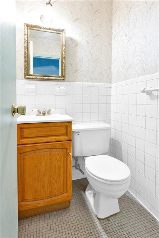 bathroom with vanity, tile patterned floors, tile walls, and toilet