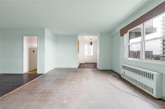 spare room featuring a notable chandelier and radiator heating unit