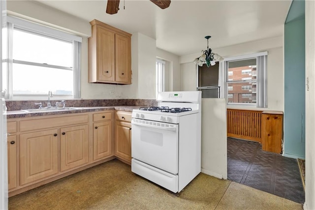 kitchen featuring decorative light fixtures, sink, light brown cabinets, and gas range gas stove