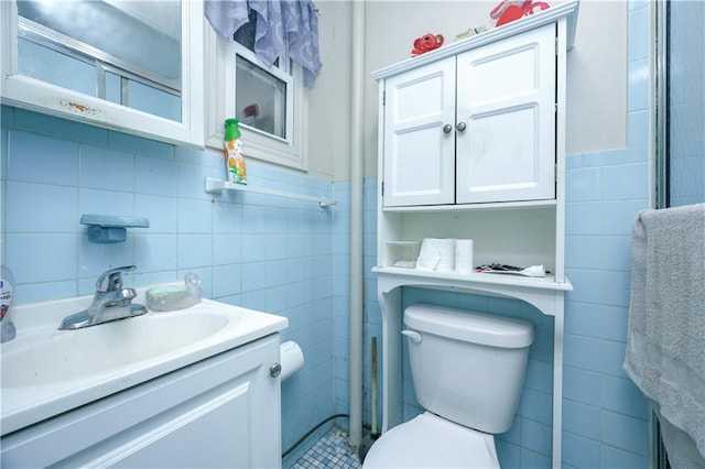 bathroom with vanity, toilet, and tile walls