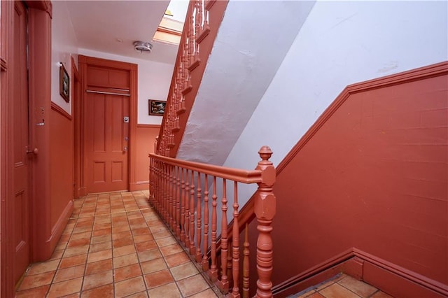 stairway featuring a skylight and light tile patterned floors