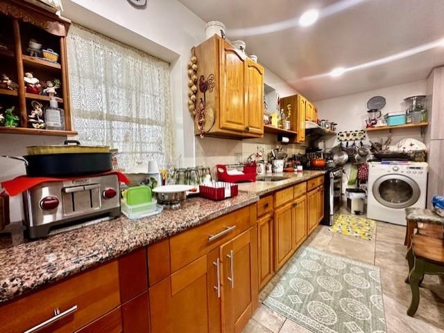 kitchen featuring sink, washer / dryer, light stone countertops, and stainless steel range oven