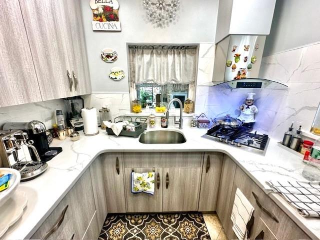 kitchen featuring tasteful backsplash, sink, stainless steel gas cooktop, and light tile patterned flooring