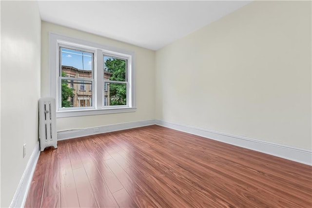 unfurnished room featuring hardwood / wood-style floors and radiator heating unit