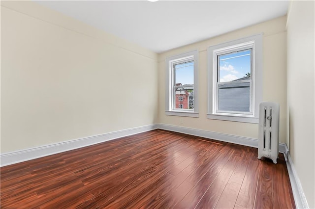 unfurnished room featuring radiator and dark hardwood / wood-style flooring