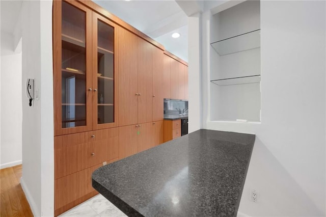 interior space featuring baseboards, dark countertops, modern cabinets, and glass insert cabinets