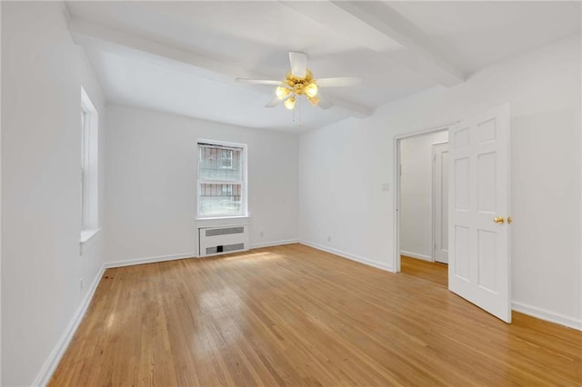 spare room with radiator, light wood finished floors, ceiling fan, beamed ceiling, and baseboards