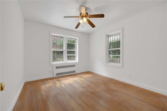 unfurnished room with hardwood / wood-style flooring, radiator, and ceiling fan