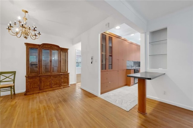 kitchen featuring a breakfast bar, an inviting chandelier, light hardwood / wood-style flooring, stainless steel dishwasher, and decorative light fixtures