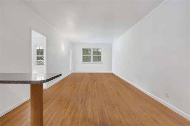 unfurnished living room featuring wood-type flooring and ornamental molding