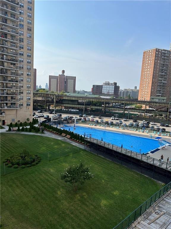 view of pool with a water view and a lawn