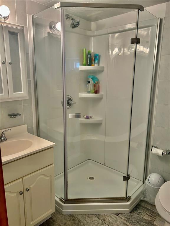 bathroom with vanity, toilet, walk in shower, and tile walls