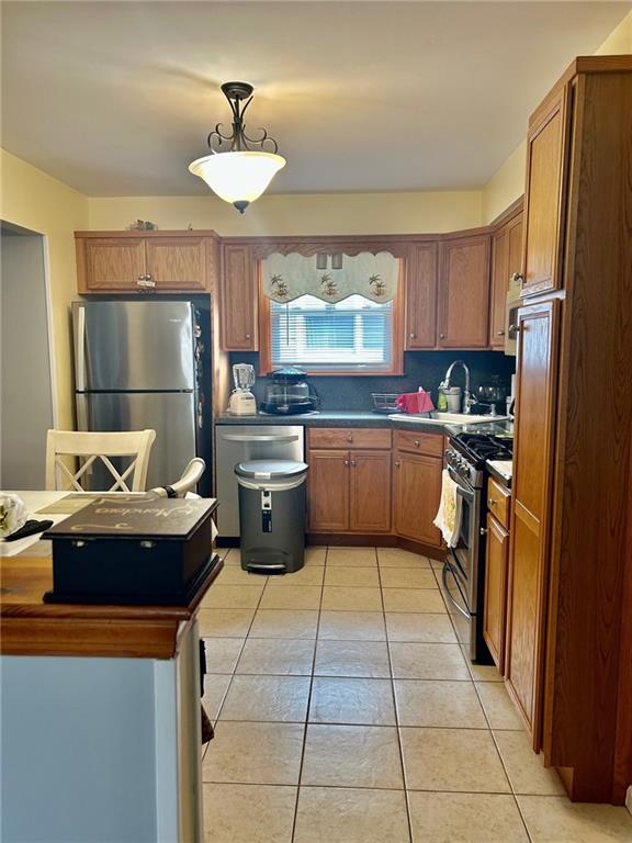 kitchen featuring sink, decorative backsplash, light tile patterned floors, and stainless steel appliances