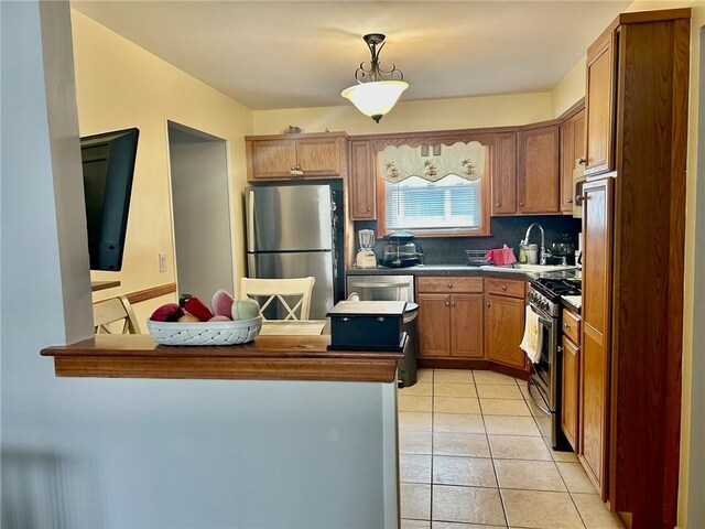 kitchen featuring light tile patterned flooring, tasteful backsplash, stainless steel appliances, sink, and kitchen peninsula