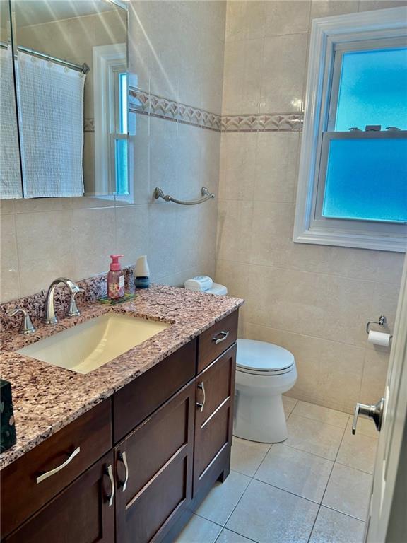 bathroom featuring tile walls, tile patterned floors, toilet, and vanity