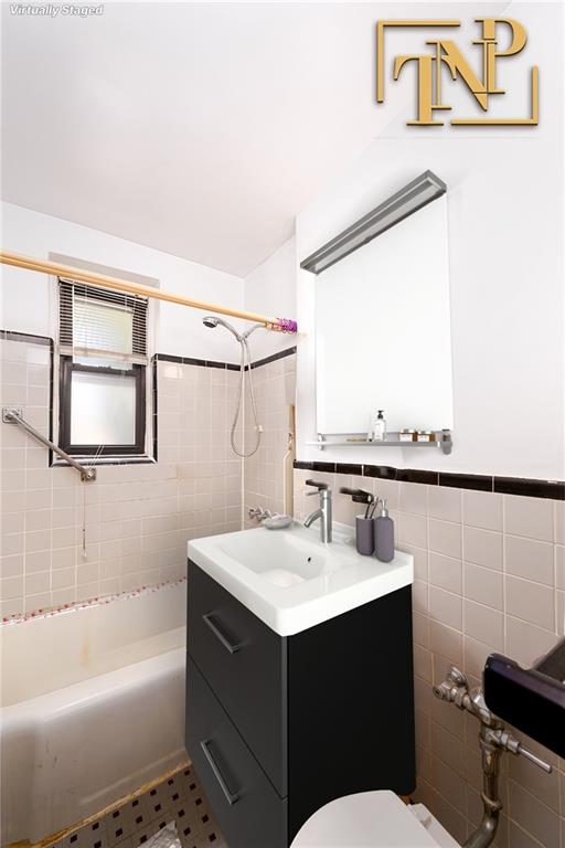 full bath with wainscoting, toilet, vanity, shower / washtub combination, and tile walls