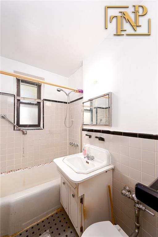 bathroom featuring tile walls, shower / bathing tub combination, toilet, wainscoting, and vanity