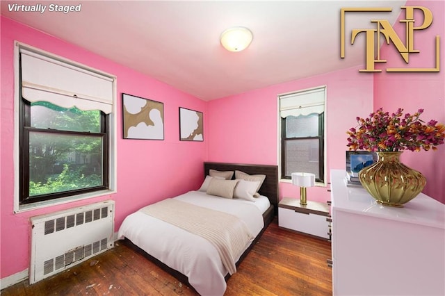 bedroom with dark hardwood / wood-style flooring and radiator heating unit