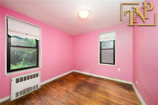 unfurnished room featuring dark hardwood / wood-style floors and radiator