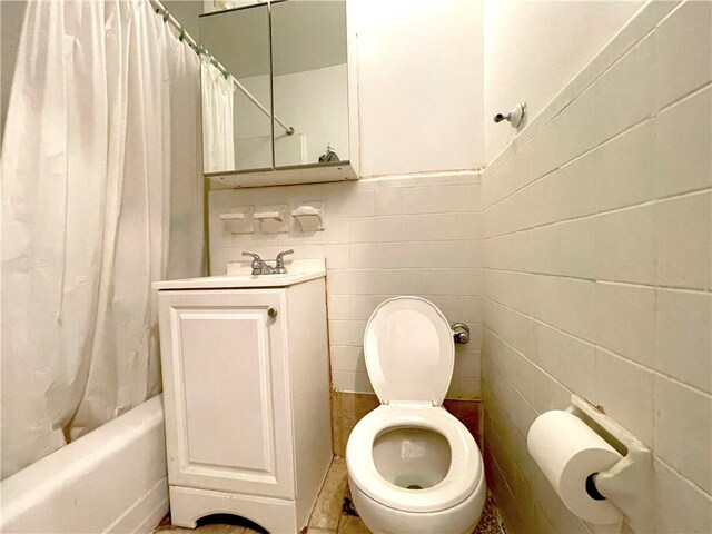 full bathroom featuring shower / bath combination with curtain, vanity, toilet, and tile walls