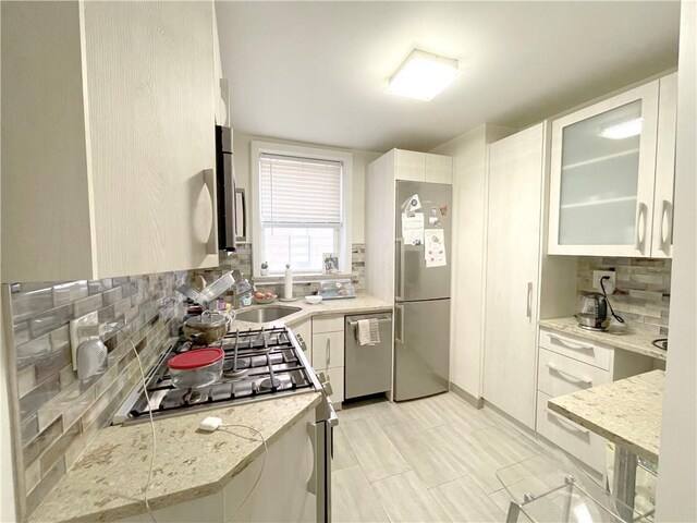 kitchen with light stone counters, white cabinetry, and appliances with stainless steel finishes