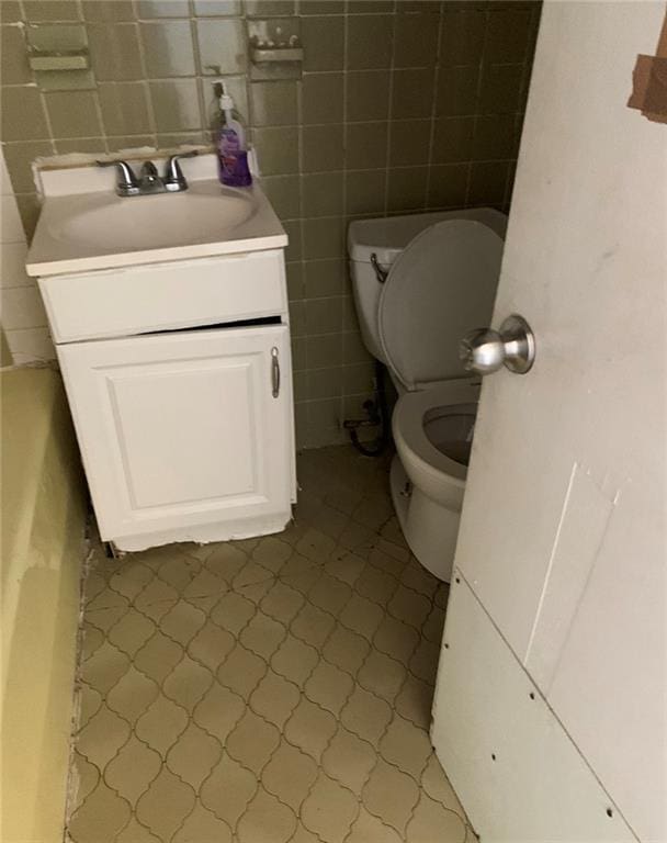 bathroom with tile walls, toilet, and vanity