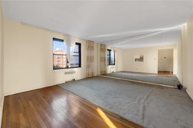 empty room with radiator heating unit and wood finished floors