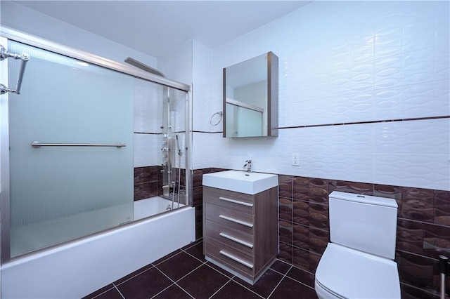 full bathroom with vanity, tile walls, enclosed tub / shower combo, tile patterned flooring, and toilet