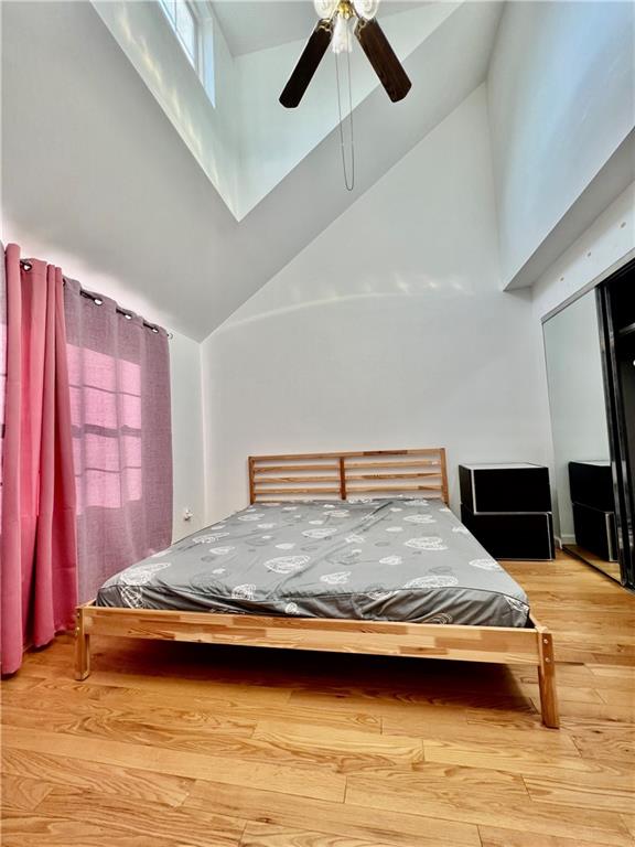 bedroom with ceiling fan, high vaulted ceiling, and hardwood / wood-style floors