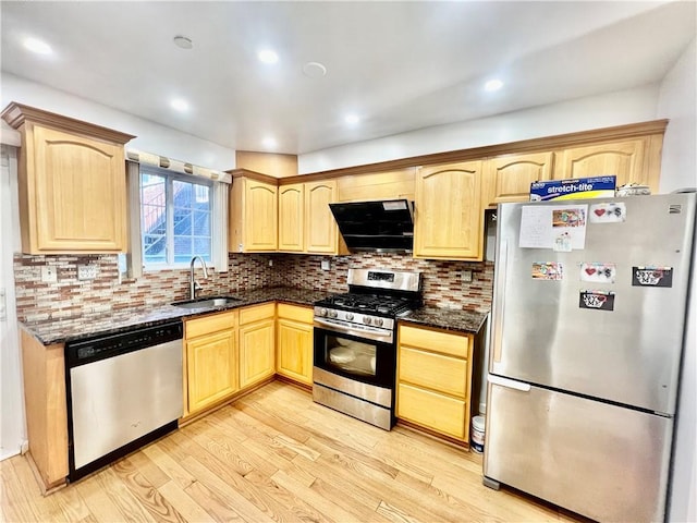 kitchen featuring appliances with stainless steel finishes, light brown cabinetry, ventilation hood, sink, and dark stone countertops