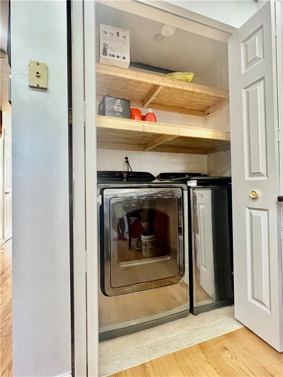 laundry room with independent washer and dryer and light hardwood / wood-style flooring