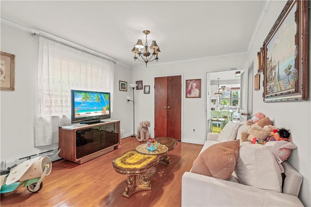 living room with ornamental molding, a baseboard heating unit, a chandelier, and light wood-type flooring