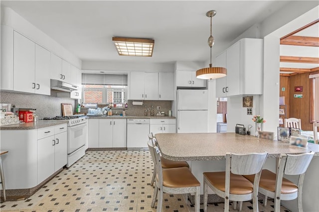 kitchen with white appliances, white cabinets, a kitchen breakfast bar, hanging light fixtures, and kitchen peninsula