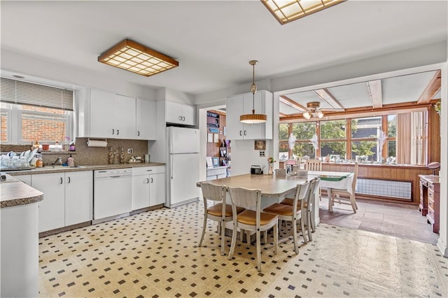 kitchen with white appliances, backsplash, white cabinets, hanging light fixtures, and ceiling fan