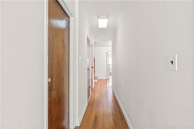 corridor with light hardwood / wood-style flooring and ornamental molding