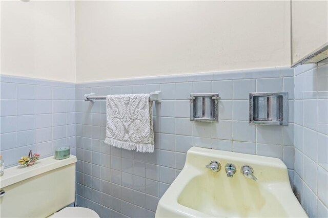 bathroom featuring tile walls and toilet