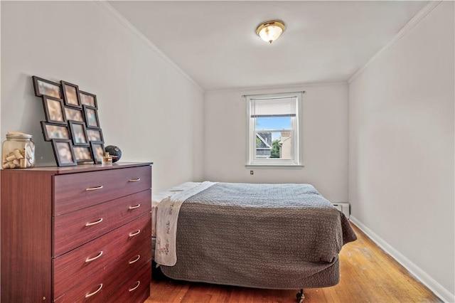 bedroom featuring crown molding and light hardwood / wood-style flooring