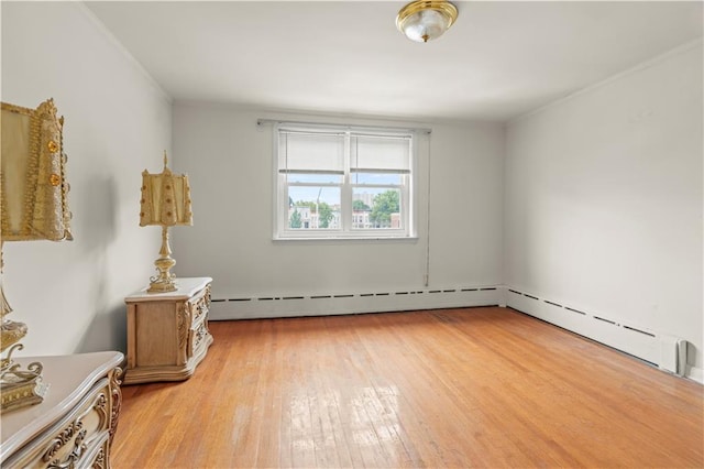 empty room featuring light wood-type flooring and a baseboard heating unit