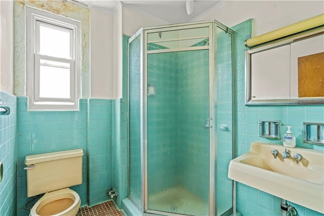 bathroom featuring tile patterned floors, toilet, walk in shower, and tile walls