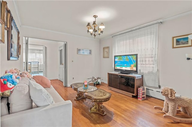 living room with an inviting chandelier, baseboard heating, crown molding, and light hardwood / wood-style flooring