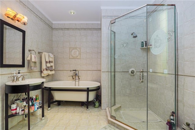 bathroom featuring independent shower and bath, ornamental molding, sink, and tile walls