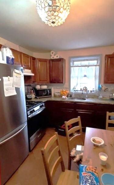 2319 W 12th St, Brooklyn, NY 11223 - kitchen with stainless steel appliances, under cabinet range hood, brown cabinets, light countertops, and a sink