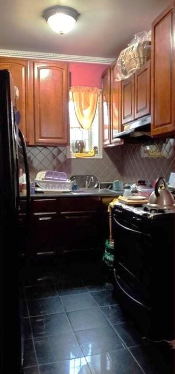 kitchen with dark tile patterned flooring, ornamental molding, decorative backsplash, and black appliances