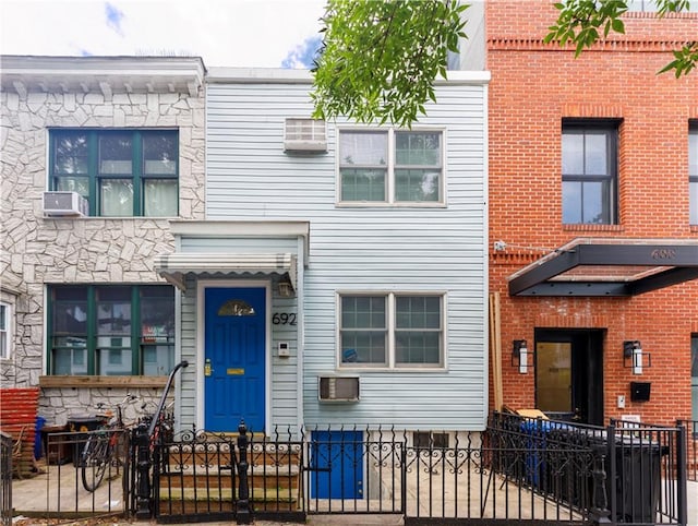 townhome / multi-family property featuring a fenced front yard, a gate, and cooling unit